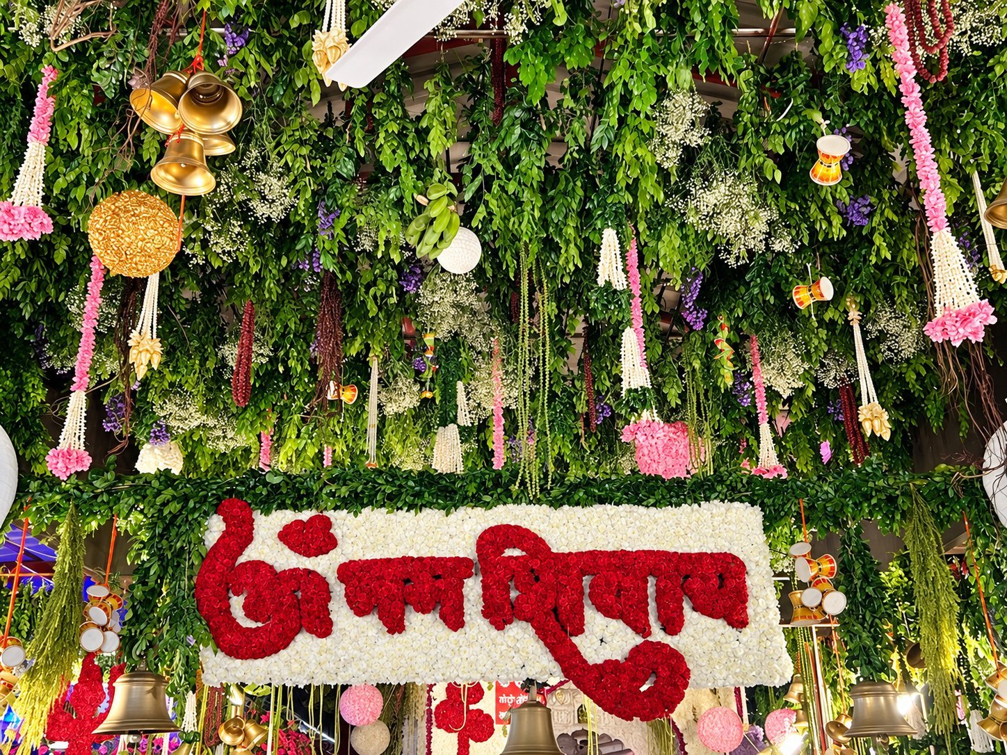 Jai Mata Di written in red roses beneath a green floral canopy