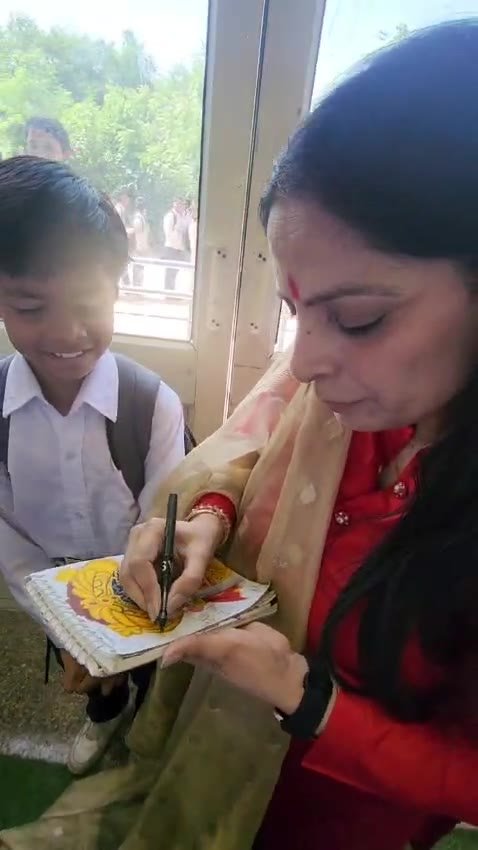 Isha Saini signing a student's painted artwork