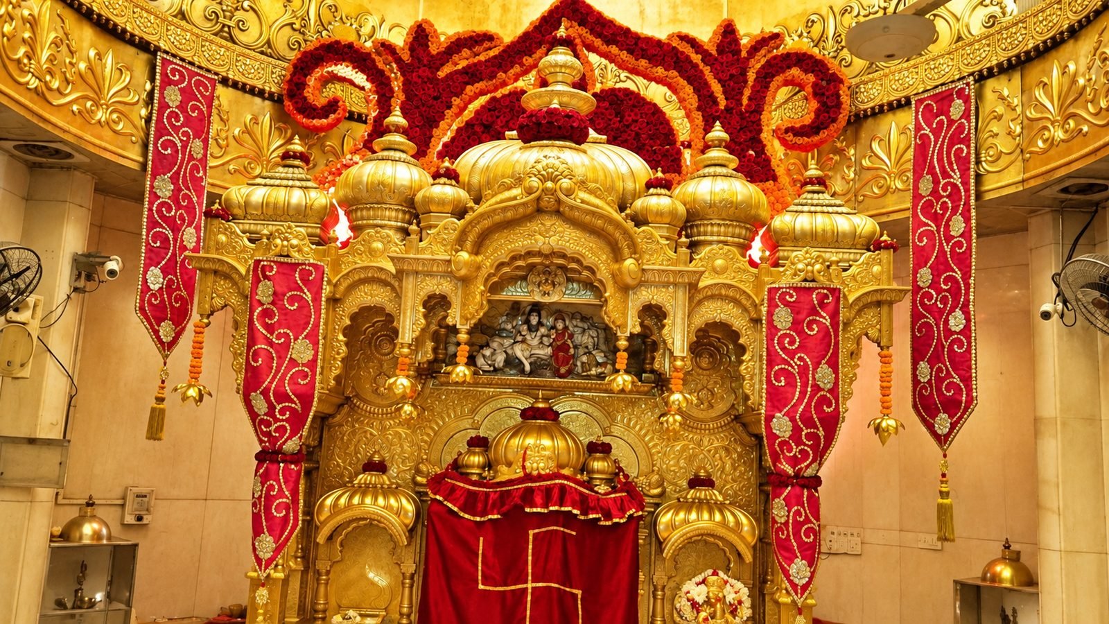 Golden shikhara facade crowned with red rose swirls at Siddhivinayak